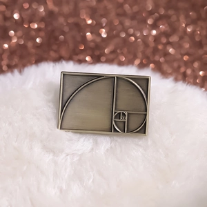 Antique brass Fibonacci golden ratio geometric lapel pin brooch on soft white fur texture