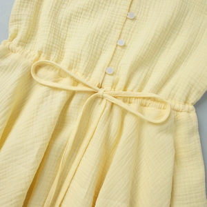 Detail of yellow cotton muslin dress showing waist drawstring and white buttons
