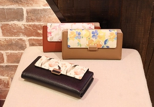 Detailed close-up of three long PU leather wallets with elegant floral prints and metal buckles