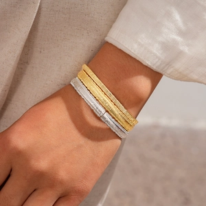 Three-piece 18k gold and silver plated bangles with textured weave on a woman's wrist