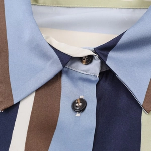 Close-up of the lapel collar and button detail on a vertical striped satin shirt