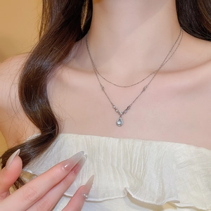 Detail of silver stainless steel double chain necklace with blue teardrop pendant