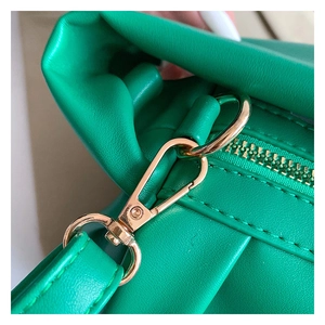 Macro shot of durable golden metal hooks and fine stitching on a green leather handbag
