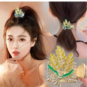 Détail d'une pince à cheveux dorée avec strass jaunes et feuilles en émail vert
