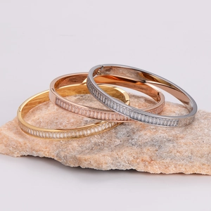 Three minimalist stainless steel zircon bangles in gold, rose gold, and silver finishes