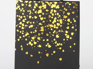 Detail of premium black paper gift bag featuring elegant gold foil heart patterns