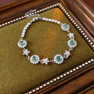 Détail d'un bracelet tennis en argent avec pierres vertes sur velours olive