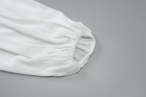 Dettaglio della trama del tessuto bianco e polsino elastico sulla manica della camicia