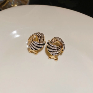 Close-up of gold-plated knot earrings with rhinestones and black enamel detail