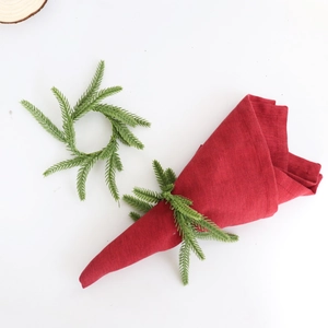 Close-up of Norfolk pine needle napkin ring with a festive red cloth on white background