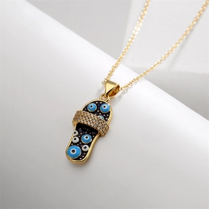 Detail of a gold flip-flop pendant with evil eye patterns and micro-inlaid zircons