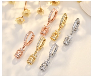 Detailed display of crown pendant earrings in rose gold, gold, and silver finishes
