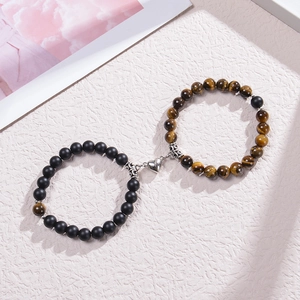 Détail de bracelets de couple en perles noires mates et oeil de tigre avec fermoir cœur aimanté