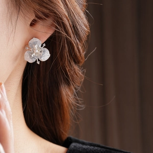 Detail of silver petal earrings with crystal center worn on a model's ear
