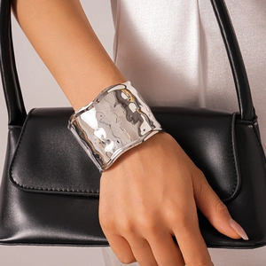 Detail of silver textured wide cuff bracelet showing unique hammered metal surface finish