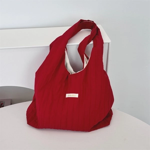 Detail of red pleated tote bag featuring a white fabric label and soft fabric texture