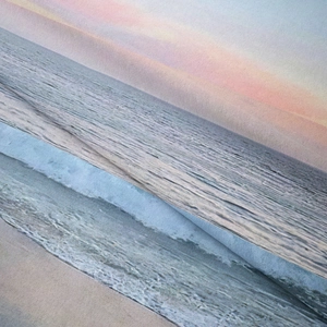 Detail of bohemian tapestry fabric showing sunset ocean waves print with a soft texture