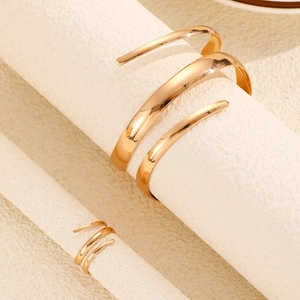 Detalle macro de conjunto de anillo y brazalete de espiral dorada con acabado metálico