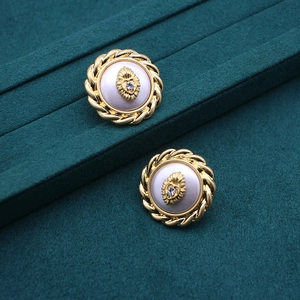 Close-up of vintage gold disc earrings with pearl inlay and central heart rhinestone detail