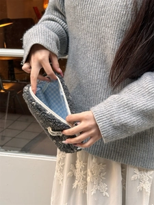 Détail d'une trousse en peluche montrant la doublure à carreaux bleus et la fourrure grise