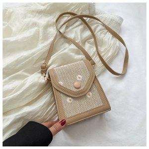 Detail of straw woven phone bag with daisy embroidery and adjustable PU strap