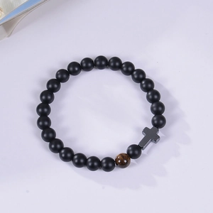 Detail of matte black beads bracelet with tiger eye stone and a metal cross charm