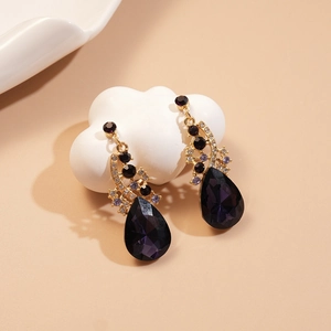 Macro shot of purple teardrop crystal earrings with gold plating and sparkling zircons