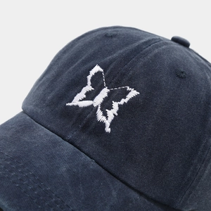Close-up of butterfly embroidery detail and cotton texture on a vintage baseball cap