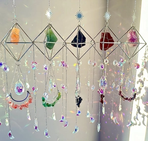 Detail of five crystal suncatchers with natural stones casting rainbow light on a white wall