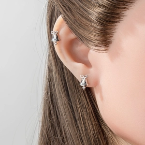 Elegant Christmas bow and bell earrings with diamond drop charms on a female model