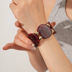 Close-up of leopard print resin bracelet with gold metal clasp on a female wrist