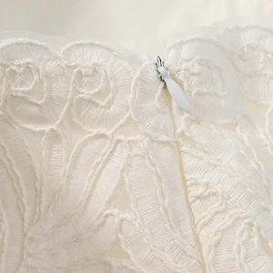 Close-up of white lace embroidery texture and invisible zipper on the elegant skirt