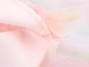 Détail macro du point de surjet sur le tulle rose et la doublure en dentelle