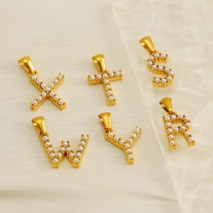 Gold letter pendants X, T, S, W, Y, R with white pearls on elegant beige fabric