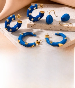 Detailed macro view of blue enamel C-shape and teardrop titanium steel earrings