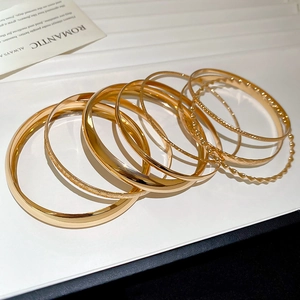 Gros plan d'un ensemble de 8 bracelets joncs en métal doré texturé pour femmes
