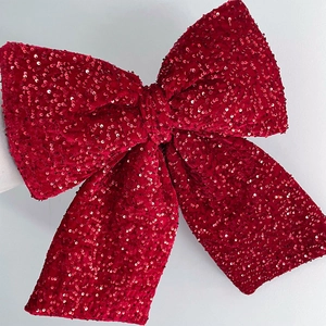 Detailed view of large red sequin bow decoration with vibrant velvet texture and gloss