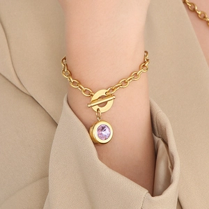 Close-up of golden OT buckle bracelet featuring a lavender crystal pendant on a wrist