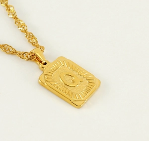 Close-up of 18K gold-plated square pendant with engraved letter Q on a twist chain