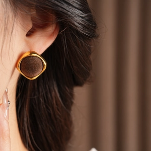 Gros plan détaillé de boucles d'oreilles géométriques en velours marron et cadre doré