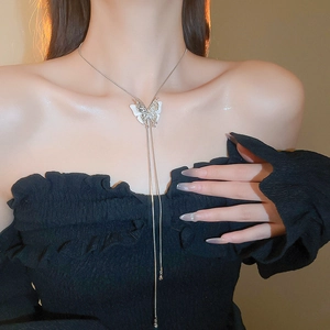 Close-up of silver butterfly tassel necklace with white wings on female model