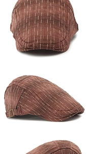 Détail de la casquette plate marron à rayures avec boucle métallique et texture rétro