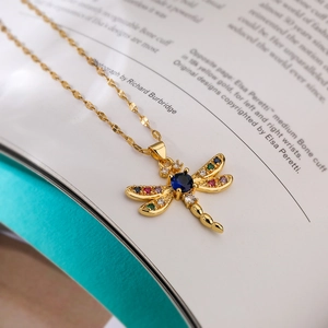 Detailed close-up of a dragonfly pendant with vibrant gemstones on a magazine background