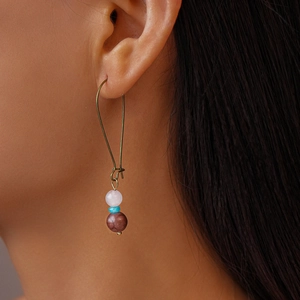 Détail de boucles d'oreilles bohèmes avec quartz rose et perles à motifs marbrés