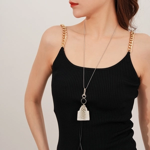 Détail d'un long collier à perles argentées avec un pendentif à franges en maille sur un mannequin