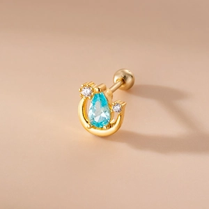 Macro shot of gold horseshoe ear stud with blue teardrop gemstone and sparkling zircons