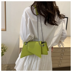 Détail du sac sous l'aisselle vert vif avec chaîne argentée et rabat géométrique