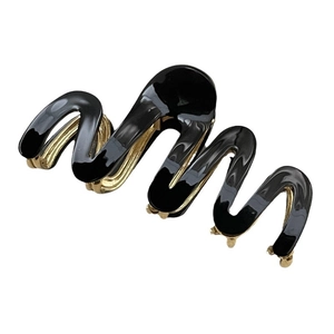 Elegant wave-shaped hair claw clip in black and gold finish with metal base for women