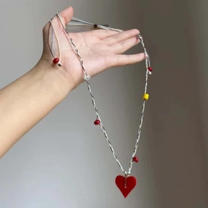 Detail of red flocked heart pendant with colorful beads on a woven necklace cord