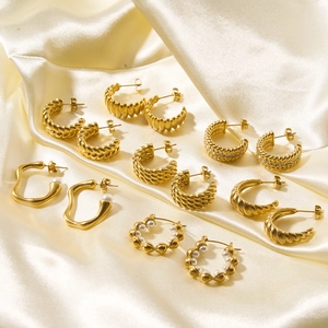 Collection of gold stainless steel earrings with pearl and crystal details on silk